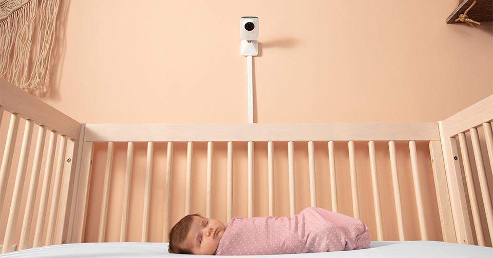 Baby in crib with smart baby monitor on wall